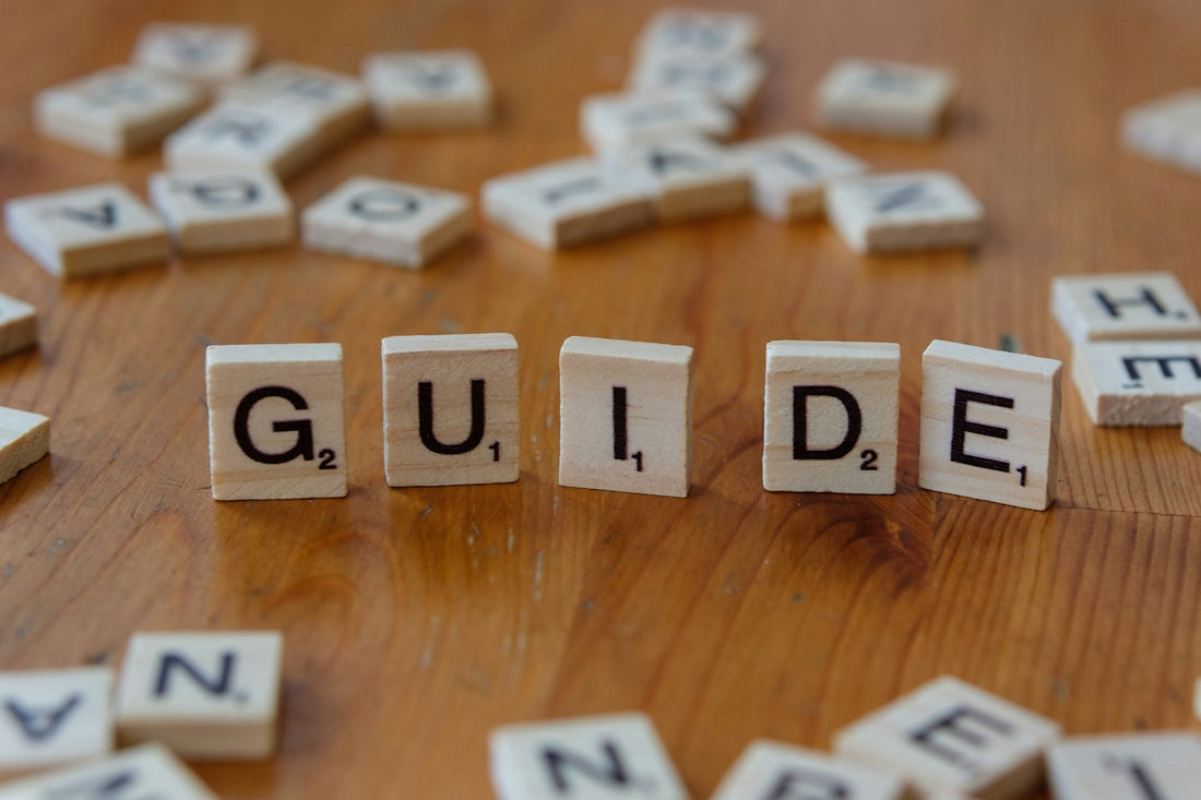 A wooden table topped with scrabble tiles spelling the word guide